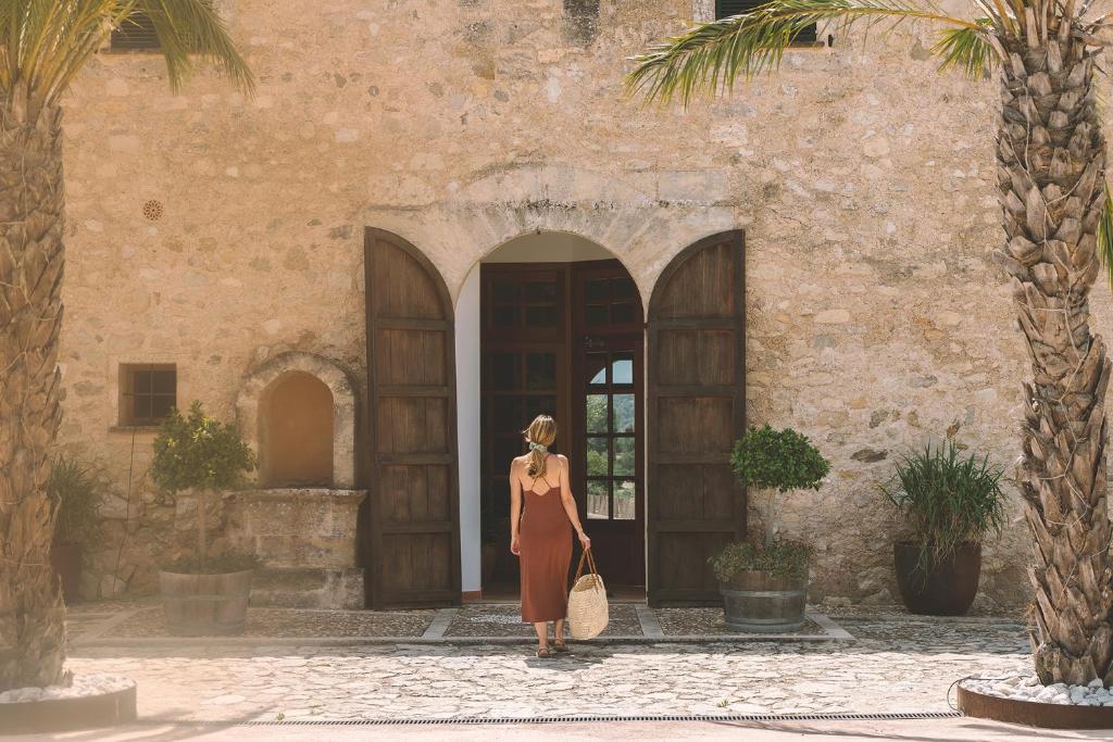 Una donna è in piedi di fronte a un palazzo di Hotel Rural Es Riquers a Porreres