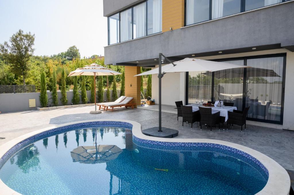 a swimming pool with a table and an umbrella at Luxury Scandinavian in Ulcinj