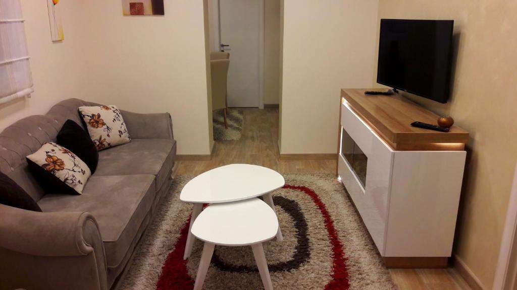 a living room with a couch and a tv and a stool at Apartment Dedinje Hill 2 in Belgrade