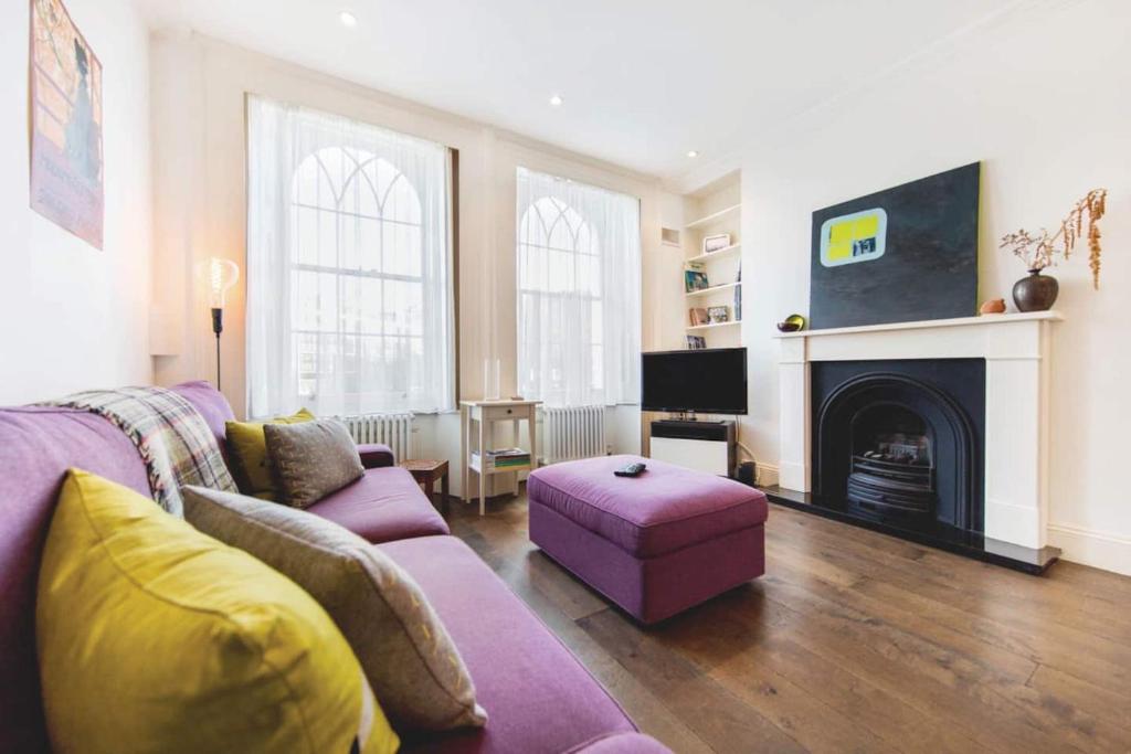 a living room with a purple couch and a fireplace at Franks Pied-à-terre in London-Quiet,Bright,Central in London