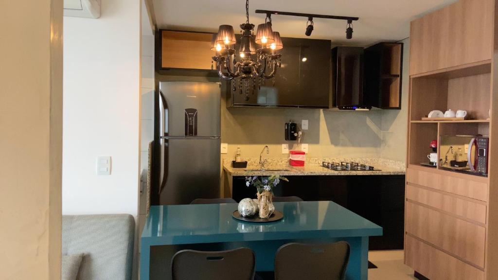 a kitchen with a blue table and a refrigerator at Flat The Expression 1705 in Goiânia