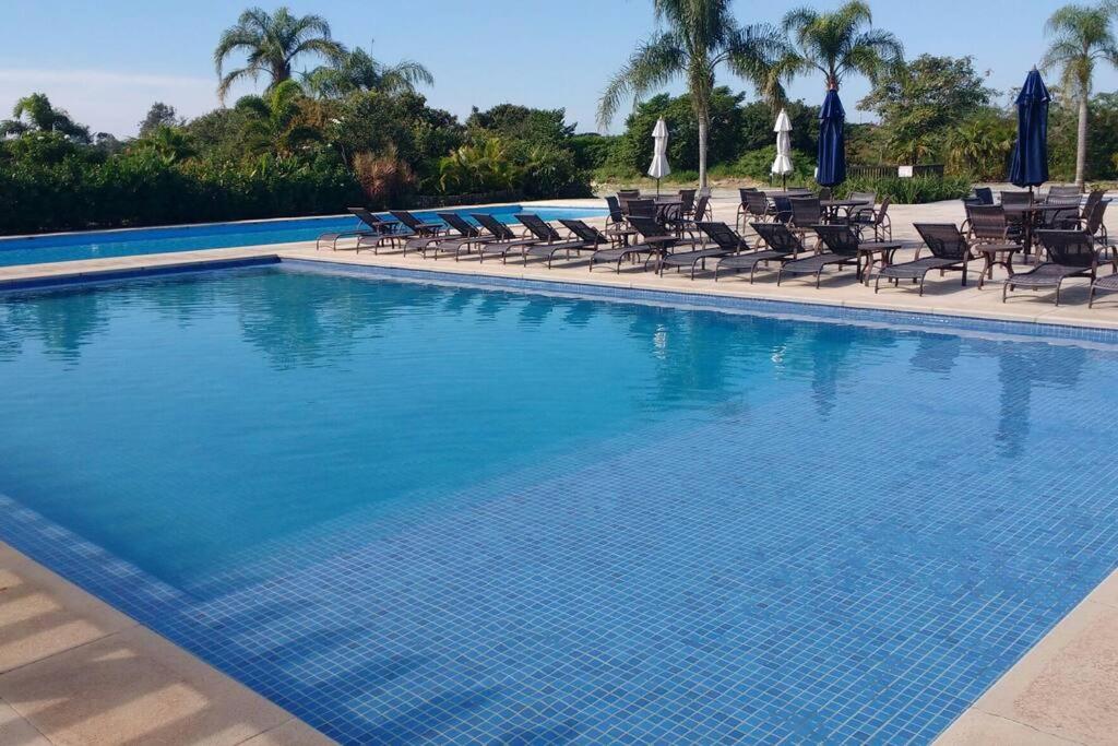 a large blue swimming pool with chairs and palm trees at Buzios Requinte & Sofisticação in Búzios