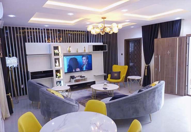 ein Wohnzimmer mit einem Sofa, Stühlen und einem TV in der Unterkunft Westpark Luxury Apartments in Ikeja