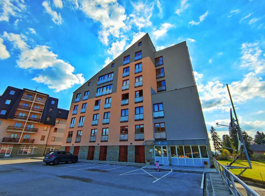 a building with a car parked in a parking lot at APARTMAN SNOW Vlašić in Vlasic