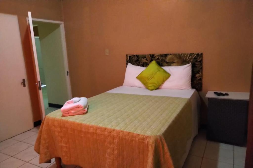 a bedroom with a bed with yellow and white pillows at Unity Villa one bedroom apartment with, cable, park wifi,near beach in Montego Bay
