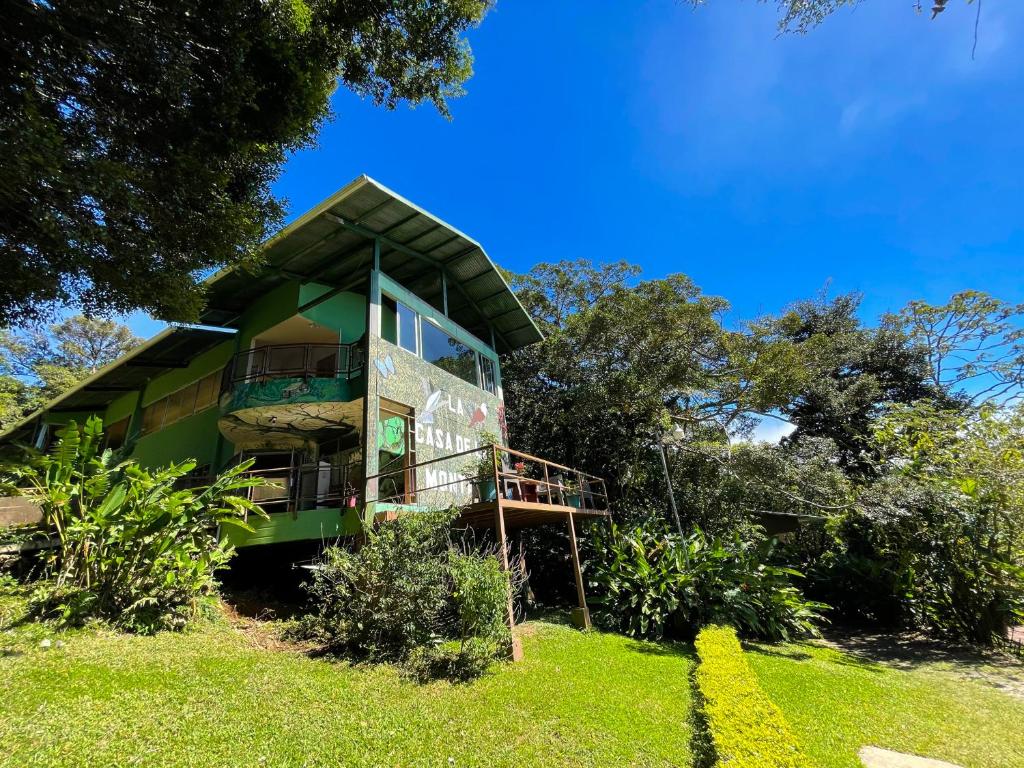 una casa verde en una colina con árboles en La Casa de la Montaña, en Monteverde