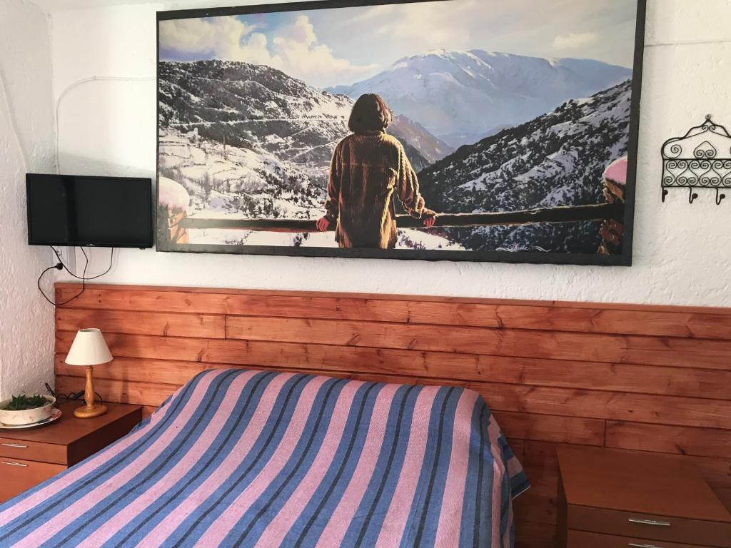 uma televisão pendurada numa parede acima de uma cama em "Casa Ibero" Bubion, Alojamiento Turistico Rural em Bubión