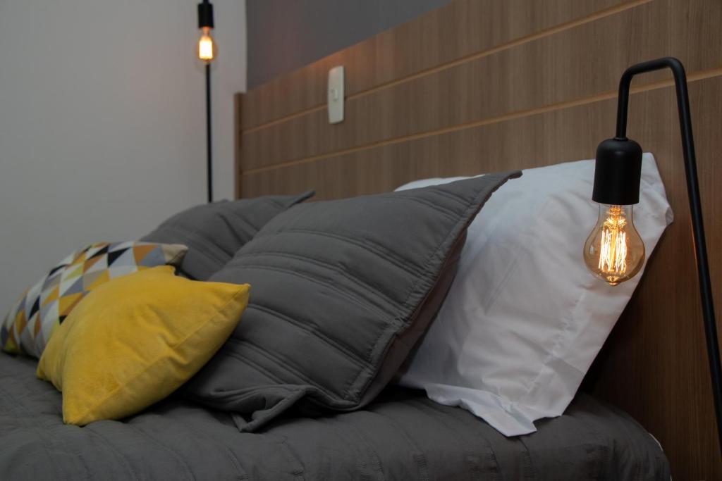 un mucchio di cuscini su un letto con lampada di Saint Moritz. Apartamento charmoso no centro de Brasília. a Brasilia