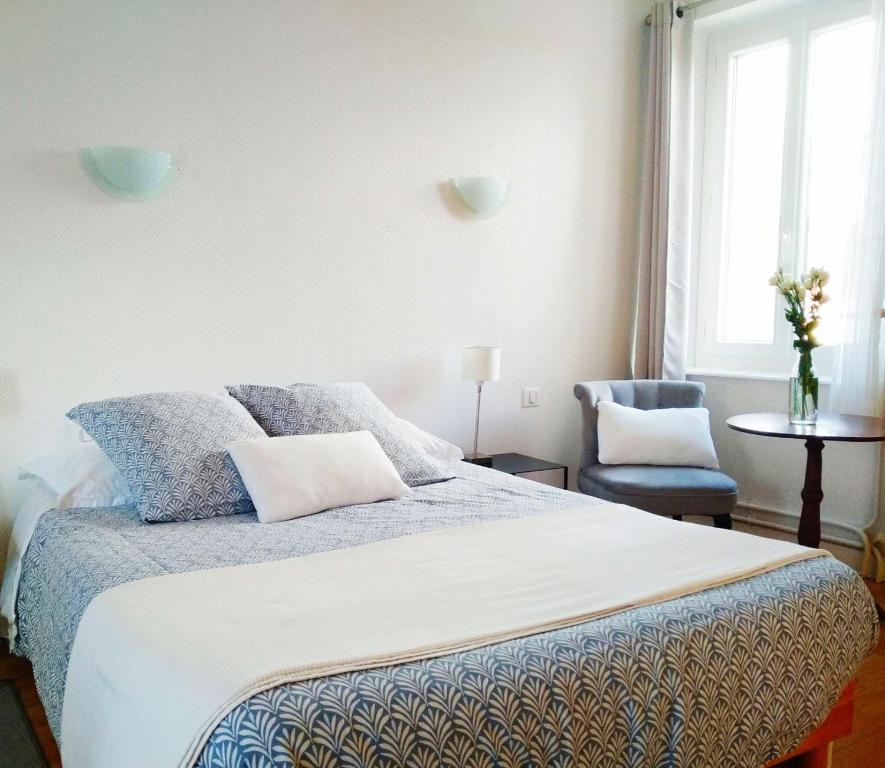 a bedroom with a bed and a chair and a window at La Maison de Thuy - Gîte en Auvergne in Gimeaux