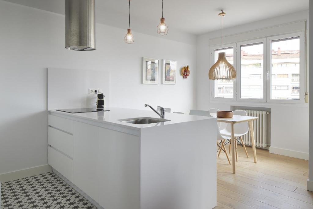 a white kitchen with a sink and a table at Aukera - Basque Stay in San Sebastián