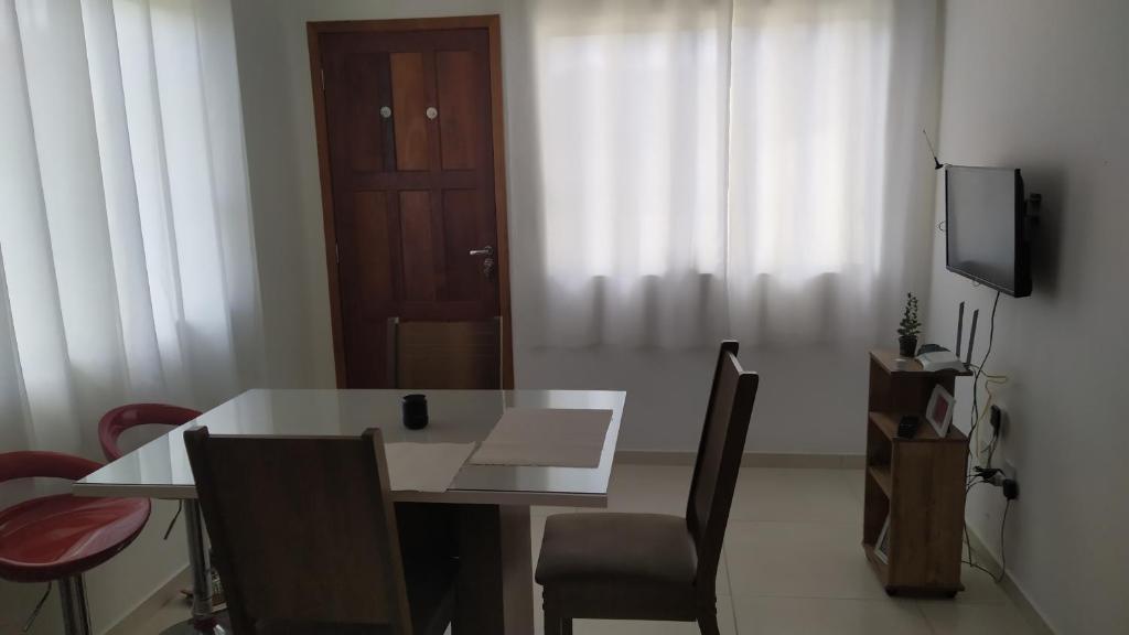 a dining room with a table and chairs and a television at Quarto,em casa compartilhada in São José