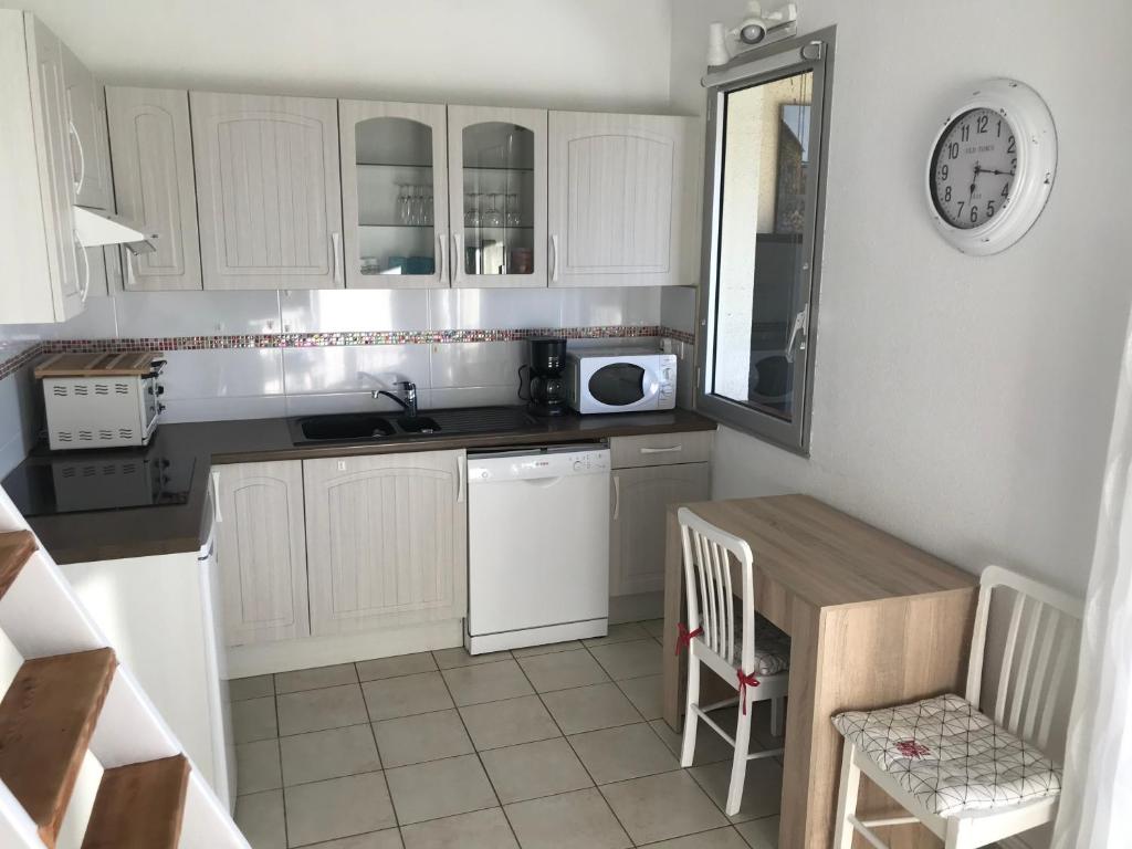 - une cuisine avec des placards blancs, une table et un four micro-ondes dans l'établissement Appartement cosy en résidence privée avec vue mer, à Soulac-sur-Mer