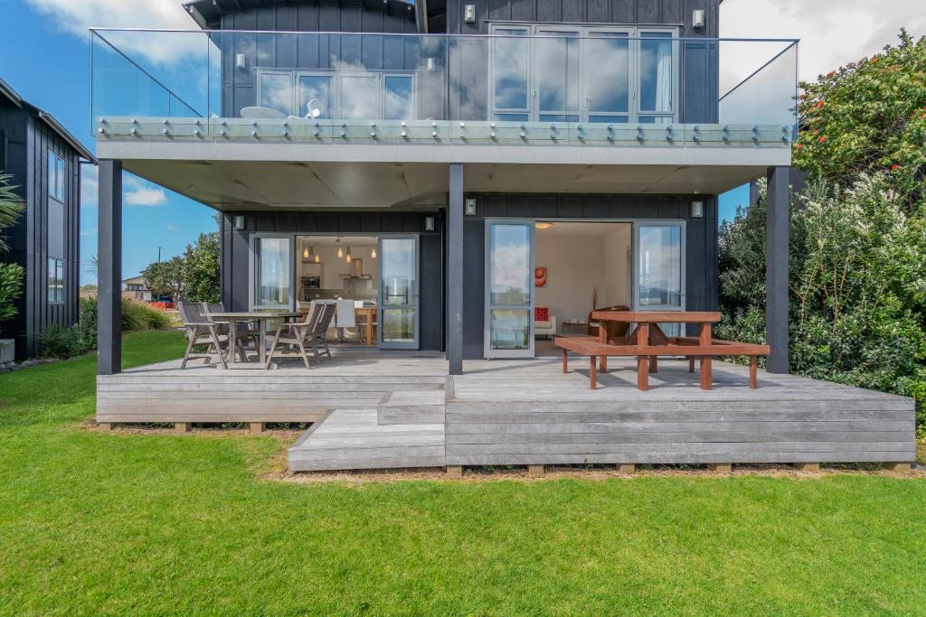 a house with a wooden deck with a picnic table at Matarangi Lakeside Gem - Golfers Dream! in Matarangi