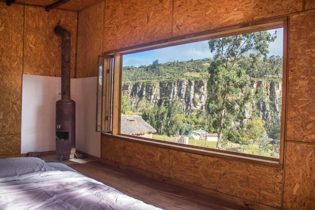 a bedroom with a large window with a mountain view at La Casa de las Estrellas in Suesca