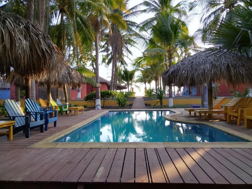 - une piscine bordée de chaises et de palmiers dans l'établissement Hotel Pez de Oro, à Monterrico