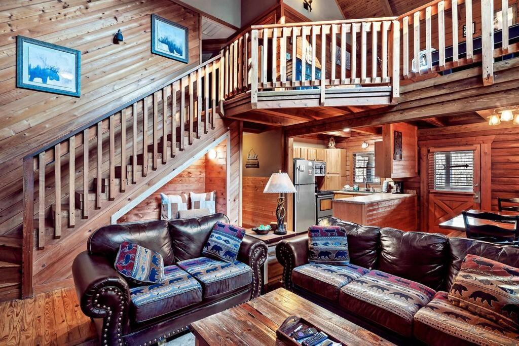 una sala de estar con muebles de cuero y una escalera. en Mama Bear's Retreat, en Sevierville