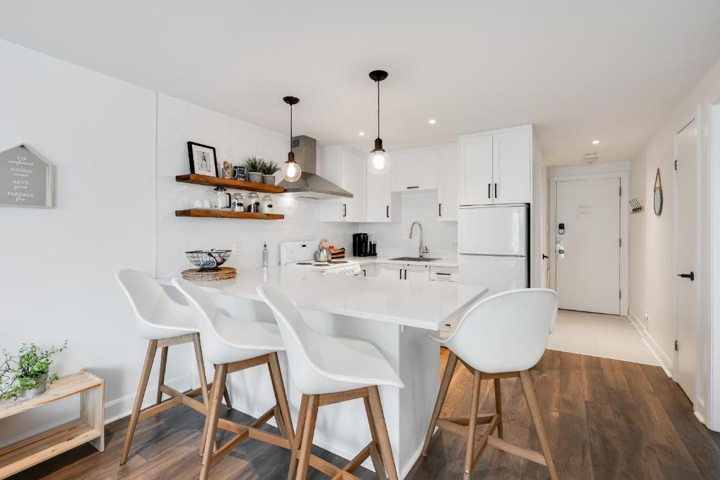 a kitchen with a white counter and white chairs at Le Lightroom by Gestion ELITE in Mont-Tremblant