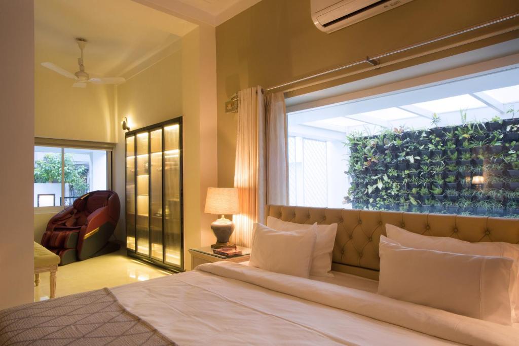 1 dormitorio con cama y ventana grande en Frangipani Suite en Nueva Delhi