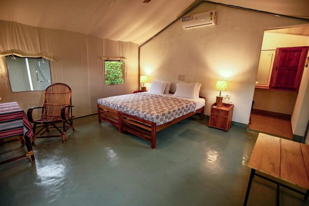 a bedroom with a bed and a table and a chair at Birds Murmur Camp, Thattekkad in Cochin