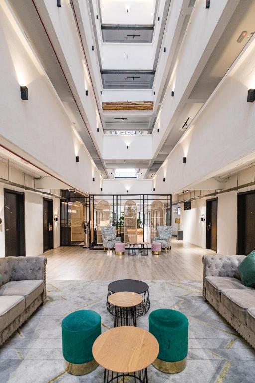 A high-ceilinged lobby with sofas, coffee tables and colorful stools.