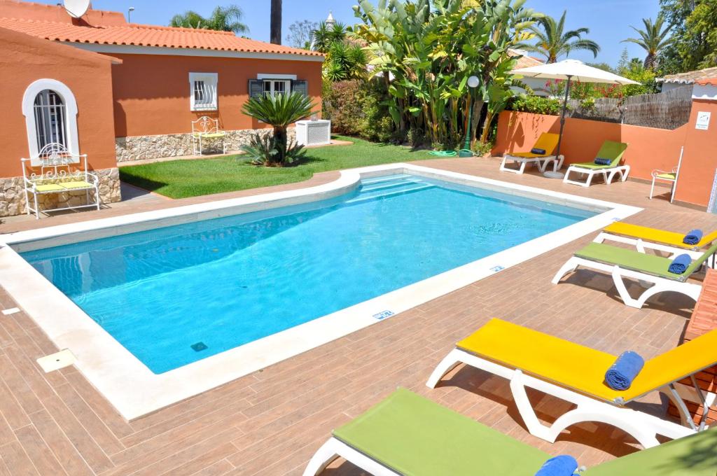 a swimming pool with chairs and a house at Fantastic Private Villa ideal for great family holidays in Quarteira