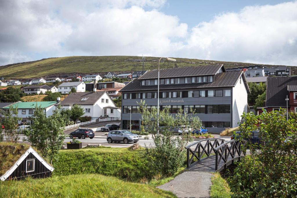 eine Stadt mit einem Gebäude und einer Straße mit Autos in der Unterkunft Hotel Runavík in Runevig