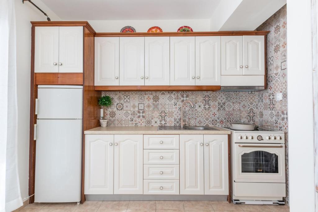 una cucina con armadietti bianchi e frigorifero bianco di AVLA LUXURY HOSPITALITY a Karpathos