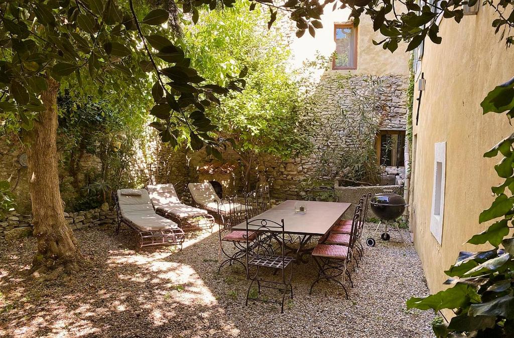 eine Terrasse mit Tisch und Stühlen und einem Baum in der Unterkunft La Marisol in LʼIsle-sur-la-Sorgue