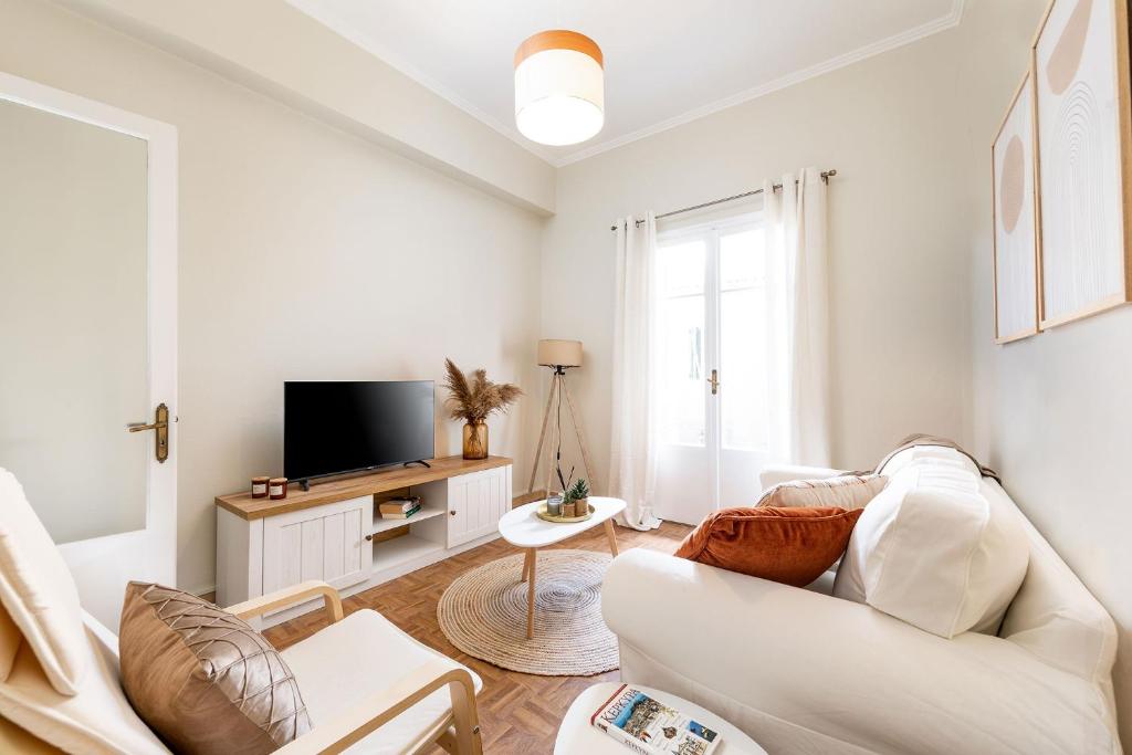 uma sala de estar com um sofá branco e uma televisão em Callisto Apartment Corfu em Corfu Town