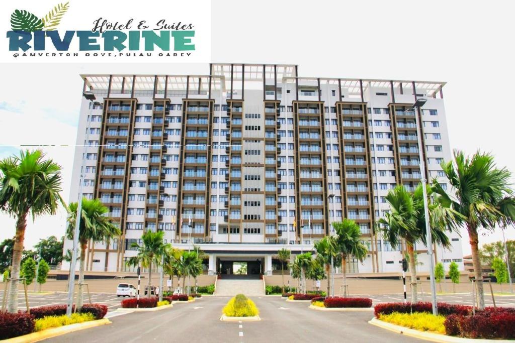 a large building with palm trees in front of it at Amverton Cove Golf & Island Resort in Banting