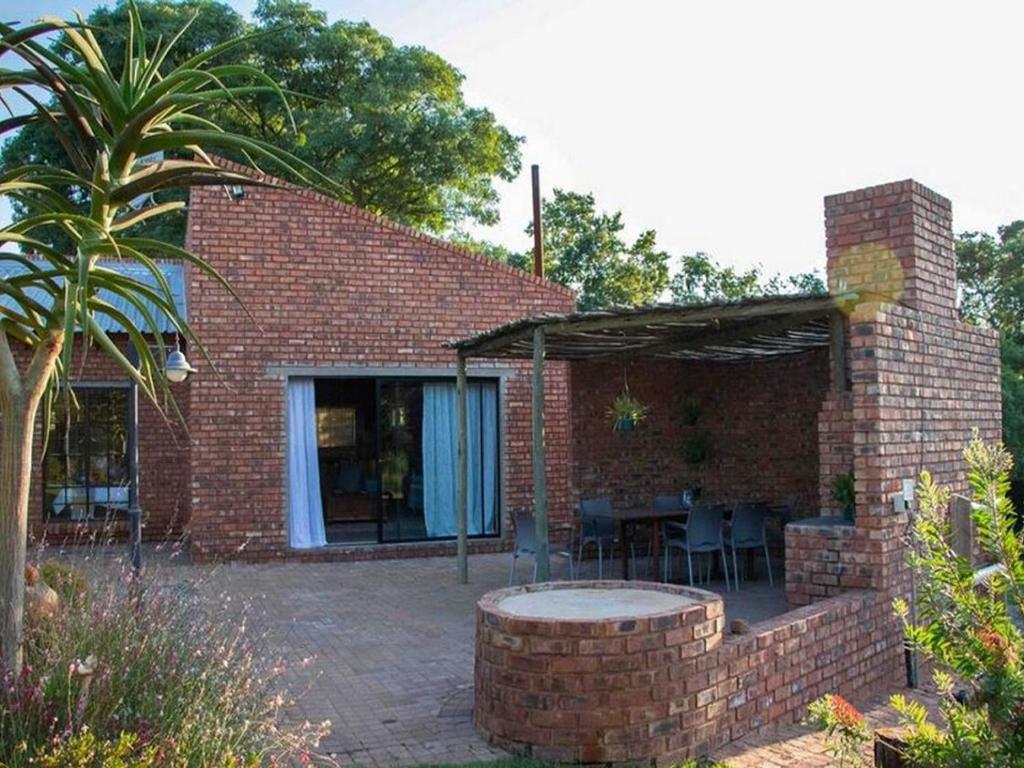 uma casa de tijolos com um pátio e uma palmeira em East of East Guest Cottage em Avondzon