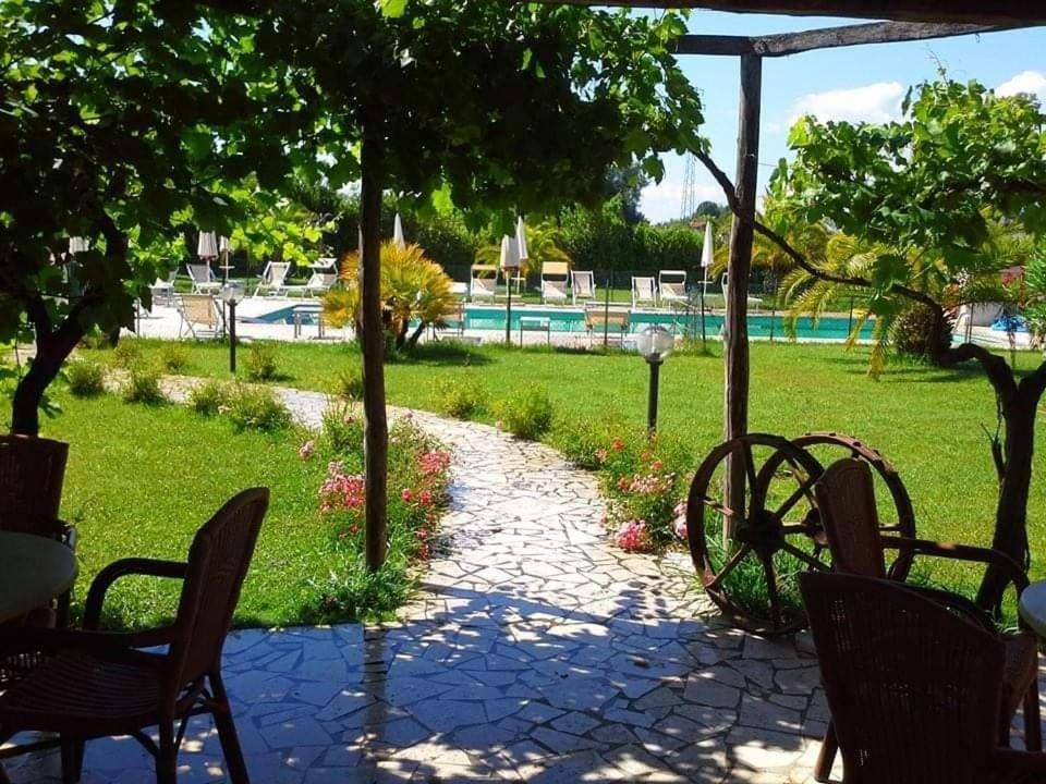 a patio with chairs and a yard with a pool at Fattoria Il Giardo in Pietrasanta