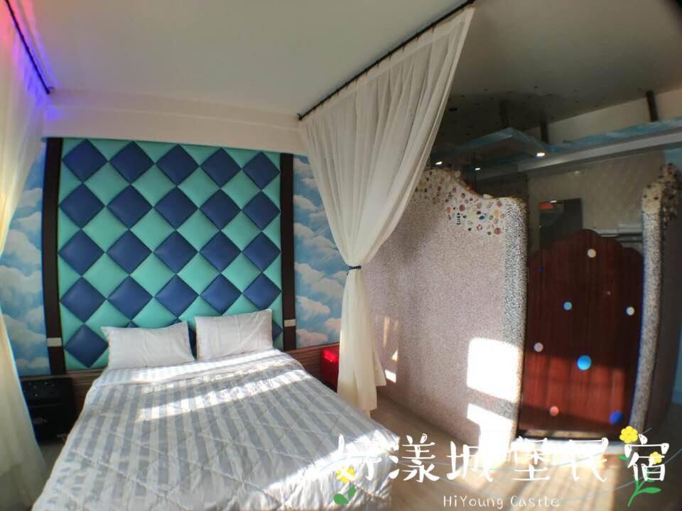 a bedroom with a bed with a blue head board at Hi Young Castle in Hengchun South Gate