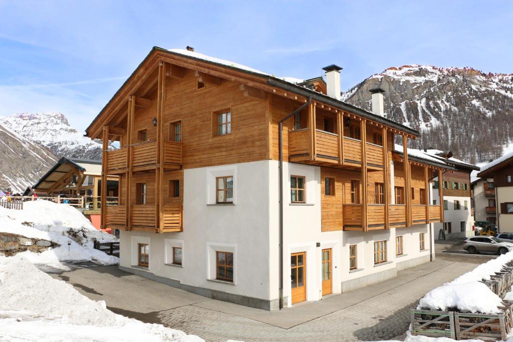 a large wooden building with snowy mountains in the background at Appartamenti Forhotel in Livigno