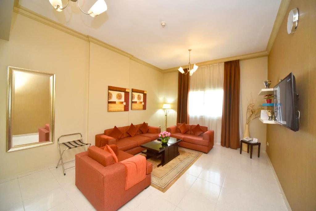 a living room with two couches and a tv at Emirates Stars Hotel Apartments Dubai in Dubai