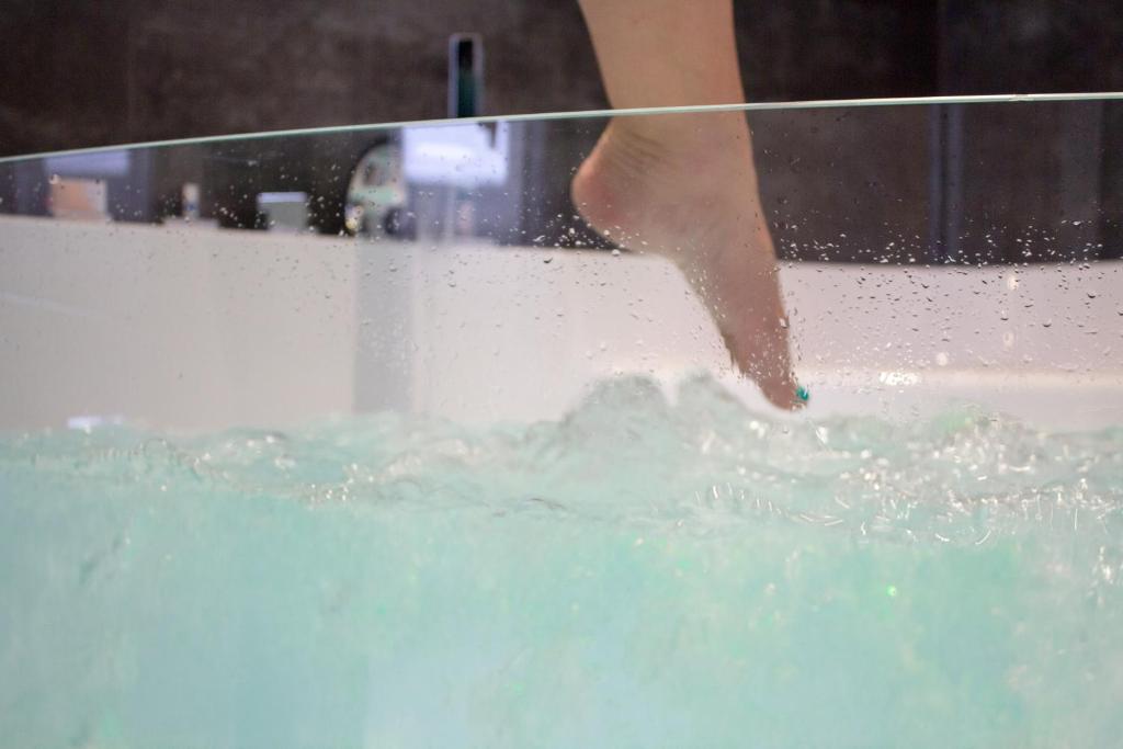 a person standing in a bath tub with water at MY SWEET HOMES - Appartements avec SPA in Colmar