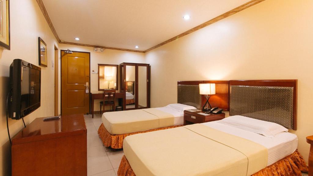 a hotel room with two beds and a television at Peace Hotel by RedDoorz in Manila