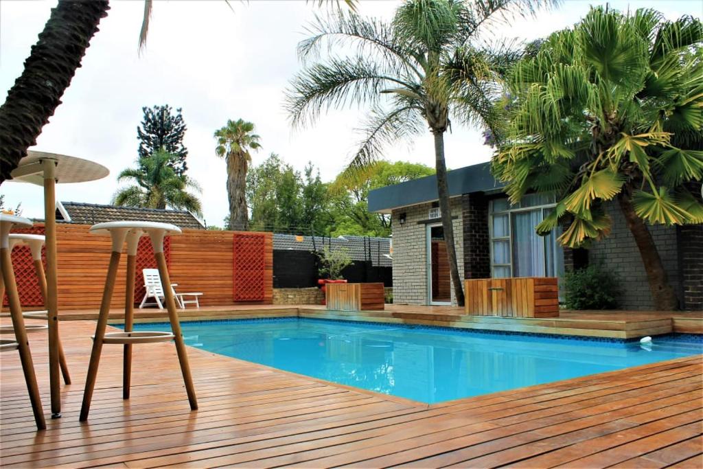 a deck with a swimming pool with two chairs and a house at FM GUEST LODGE Comfort, Tranquility & Peace of Mind in Johannesburg
