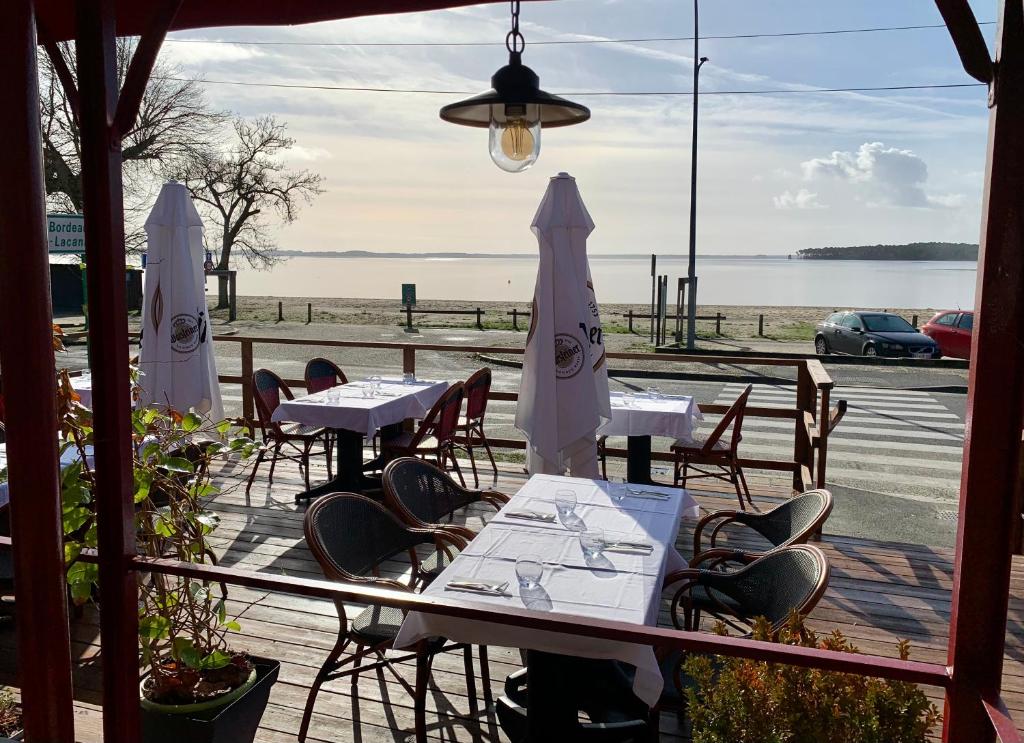 eine Terrasse mit Tischen und Stühlen und Meerblick in der Unterkunft LE MOUTCHICO in Lacanau