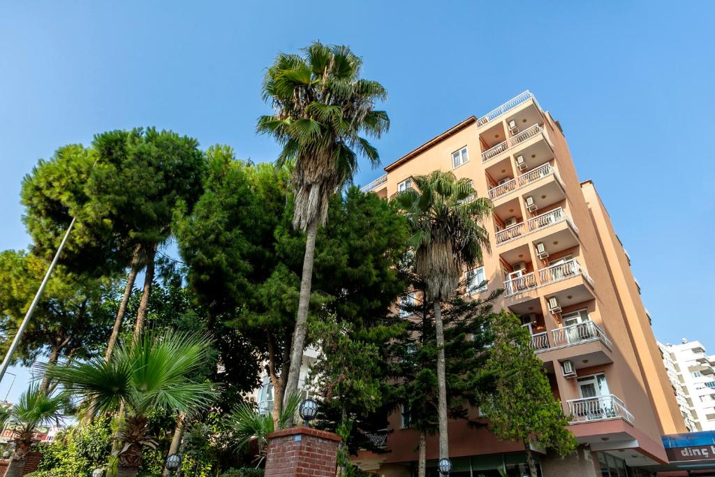 a tall building with palm trees in front of it at Lara Dinc Hotel in Antalya