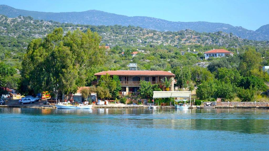 una casa sulla riva di un lago con barche di Kekova Pansiyon a Demre