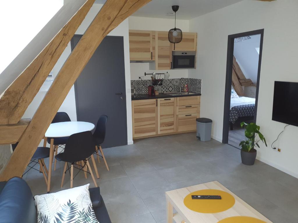 uma sala de estar com uma mesa e uma cozinha em L'élégant Gîtes de Moiscourt em Gisors