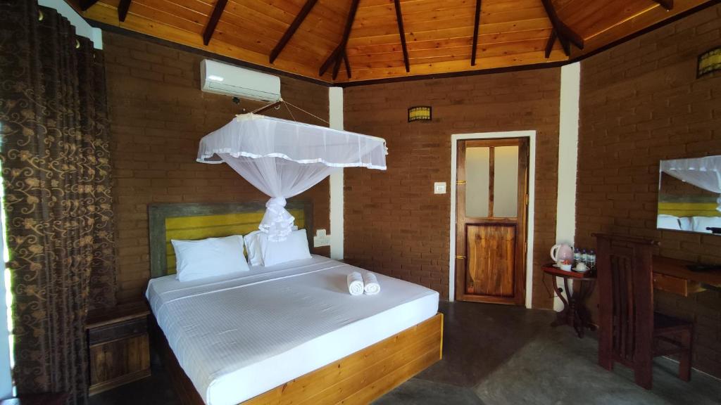 a bedroom with a white bed with a canopy at Rice Rice Villas in Tissamaharama