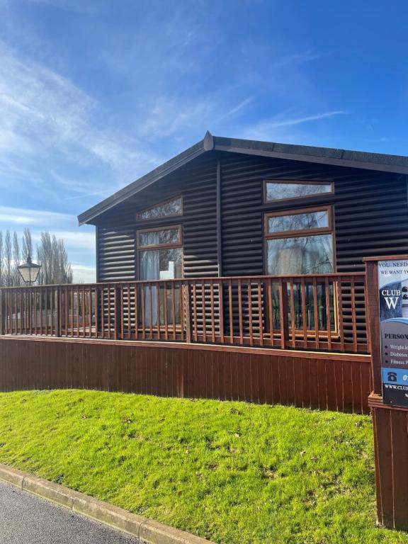 a house with a wooden deck and a sign in front of it at #3 Delightful 3 bedroom lodge - holiday home, No Hot tub 