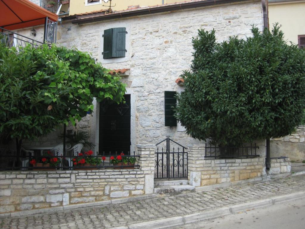 a stone building with a black door and two trees at Apartment Roby in Vrsar