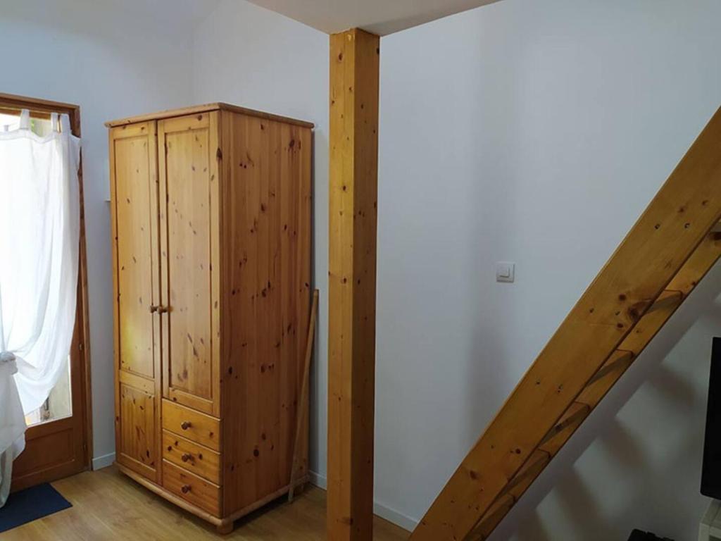 Zimmer mit einem Holzschrank neben einer Treppe in der Unterkunft Studio privé à la campagne in Guillerval