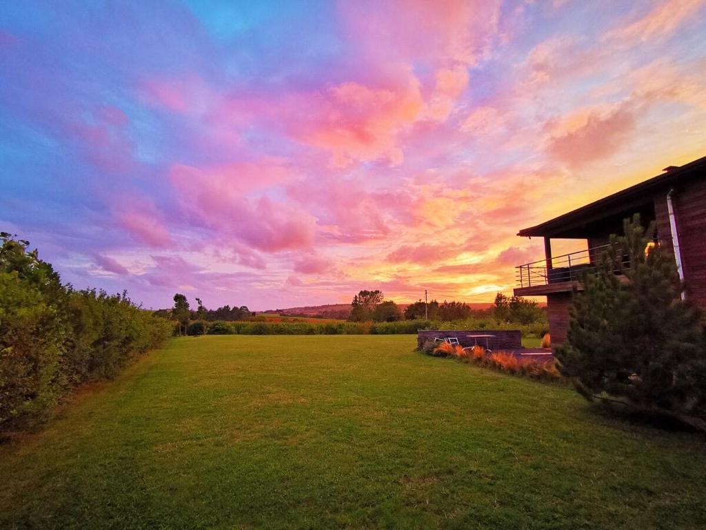 una puesta de sol sobre un campo con una casa y un campo de hierba en Coolcottage des 2 Caps, en Leulinghen-Bernes