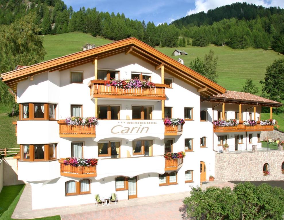 un gran edificio blanco con flores en los balcones en Residence Carin en Selva di Val Gardena