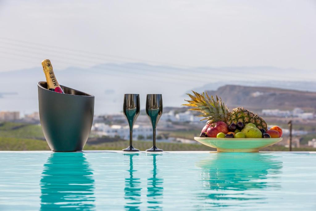 a bowl of fruit next to two forks and a bowl of fruit at White Orchid Villa in Pirgos
