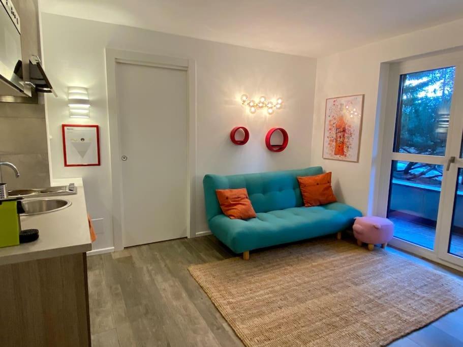 un salon avec un canapé bleu et une fenêtre dans l'établissement TRILOCALE SULLE PISTE Appena RISTRUTTURATO, à Sauze dʼOulx